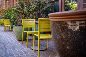 Cadeiras Amarelas E Vasos Grandes Em Um Patio De Tijolos ObPe8Lnf9TI