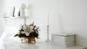 Elegant minimalist white interior with a flower arrangement and candle on a table.