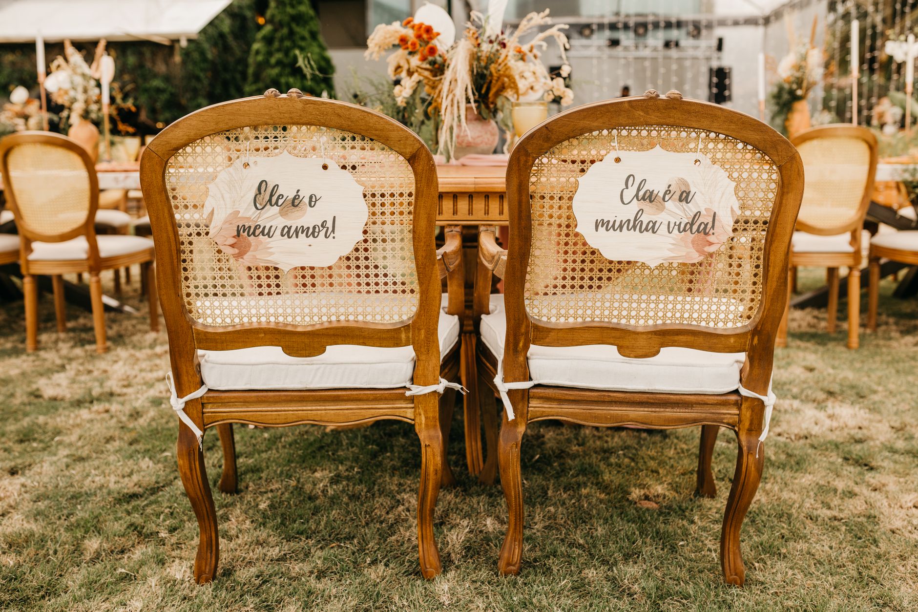 Elegant wooden chairs with personalized love messages at an outdoor wedding setup.