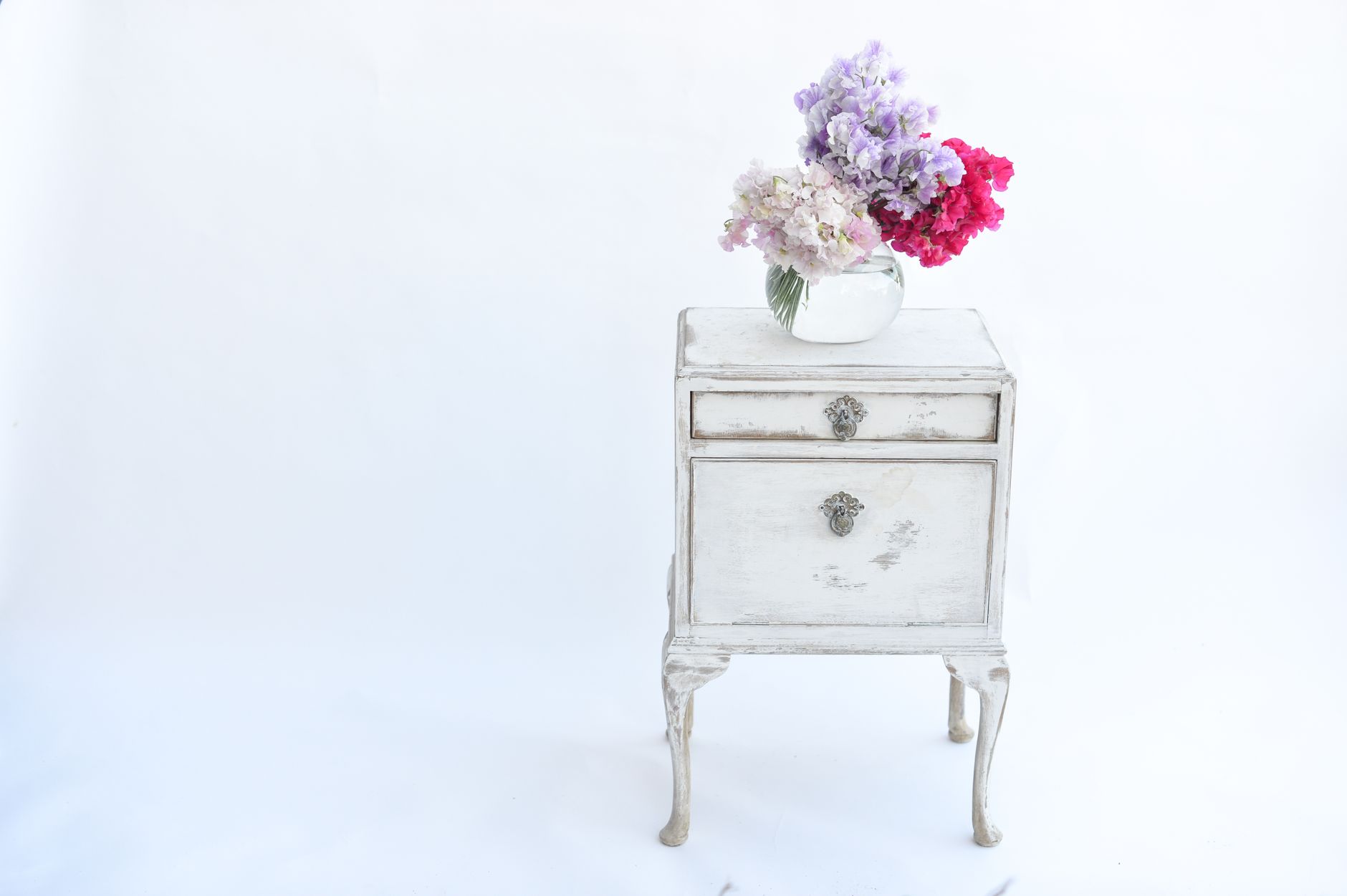 Elegant vintage nightstand with a colorful flower bouquet, perfect for classic decor themes.