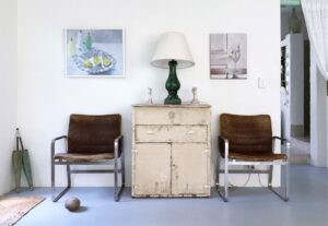 Rustic decor with vintage chairs, distressed cabinet, and art prints.