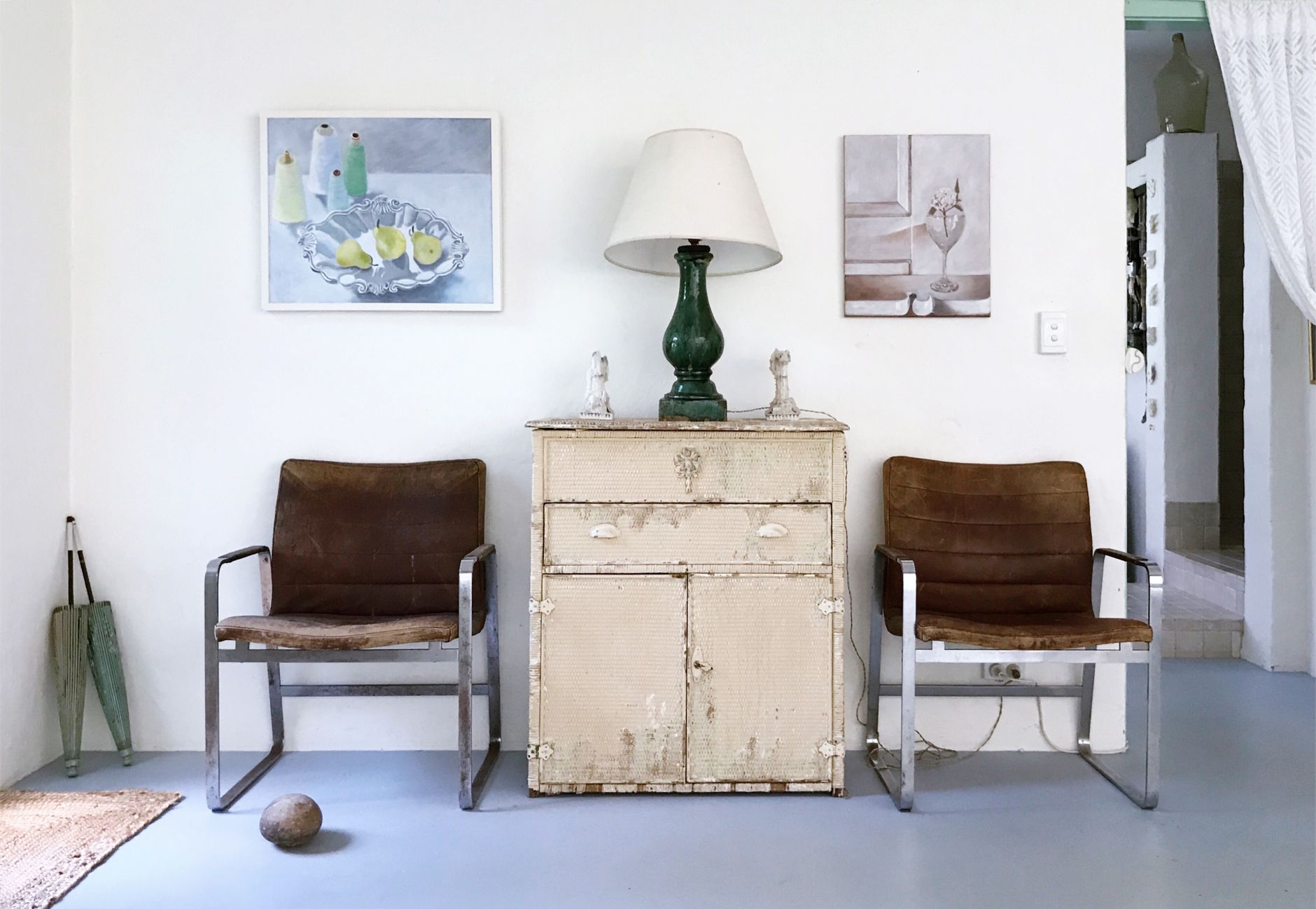 Rustic decor with vintage chairs, distressed cabinet, and art prints.